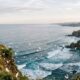 Coastal cliffs and ocean waves with drifting petals, serene memorial scene, cremation services in Apache Junction AZ